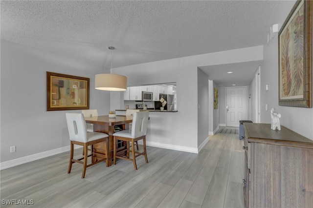 dining area with a textured ceiling and light wood-type flooring