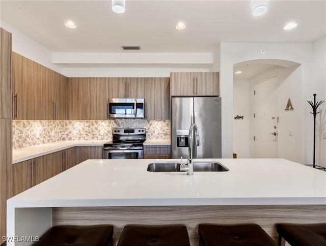 kitchen featuring tasteful backsplash, a breakfast bar, sink, and stainless steel appliances