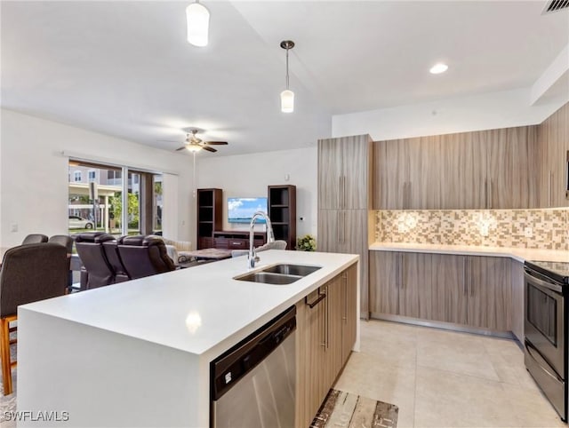 kitchen with backsplash, sink, hanging light fixtures, a kitchen island with sink, and appliances with stainless steel finishes