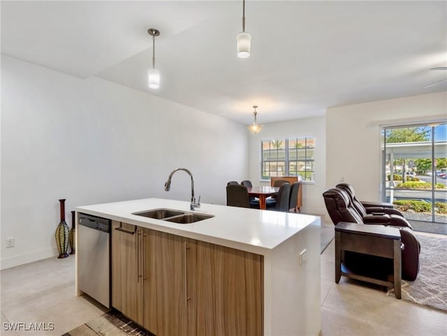 kitchen featuring hanging light fixtures, sink, stainless steel dishwasher, and a center island with sink