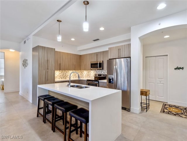 kitchen with sink, hanging light fixtures, stainless steel appliances, and a breakfast bar area