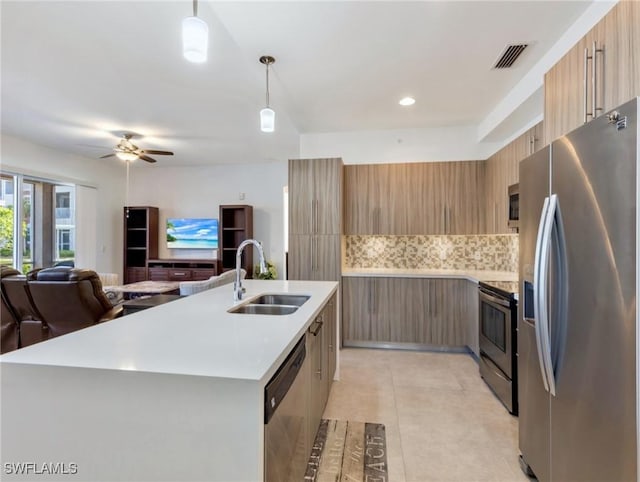 kitchen with decorative light fixtures, tasteful backsplash, sink, a kitchen island with sink, and appliances with stainless steel finishes