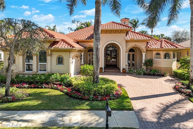 mediterranean / spanish house with a front yard and french doors