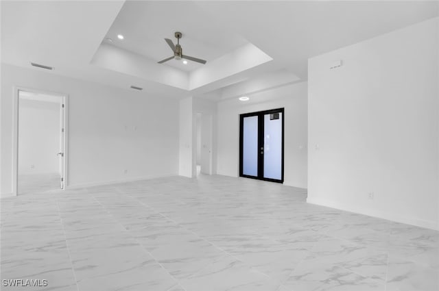 empty room with a raised ceiling, ceiling fan, and french doors