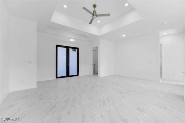 empty room featuring a raised ceiling, ceiling fan, and french doors