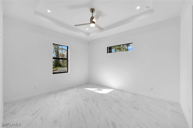 unfurnished room with ceiling fan and a tray ceiling