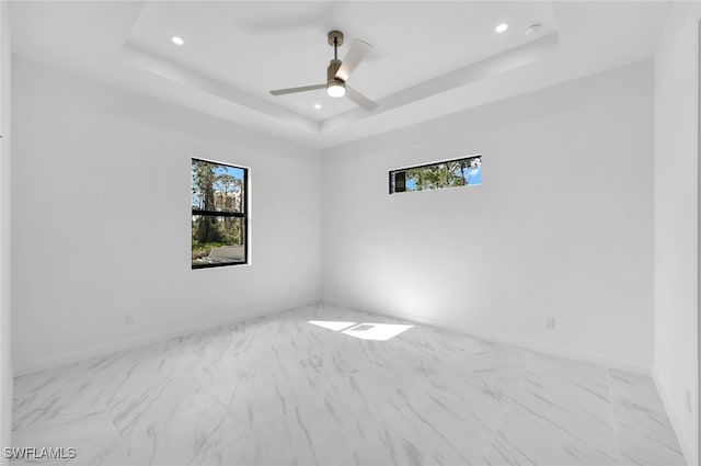 spare room with a raised ceiling and ceiling fan