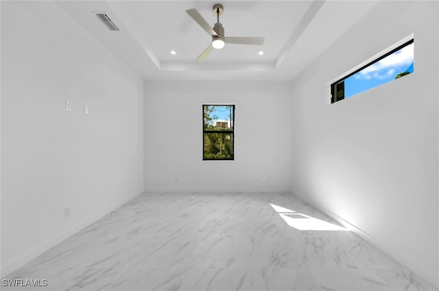 spare room with ceiling fan and a tray ceiling