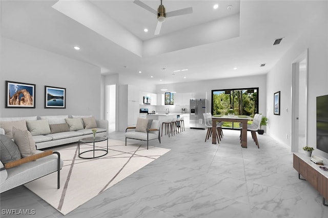 living room featuring a raised ceiling and ceiling fan