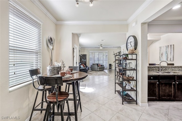 dining area featuring ceiling fan, light tile patterned flooring, crown molding, and sink