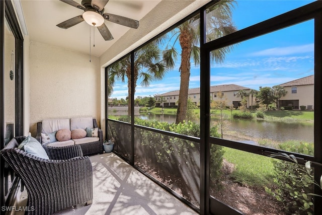 sunroom featuring ceiling fan and a water view