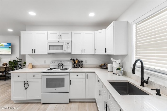 kitchen with light stone countertops, white cabinetry, sink, and white appliances