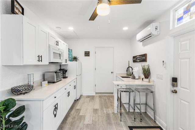 kitchen with sink, white appliances, white cabinetry, a wall mounted air conditioner, and a breakfast bar area