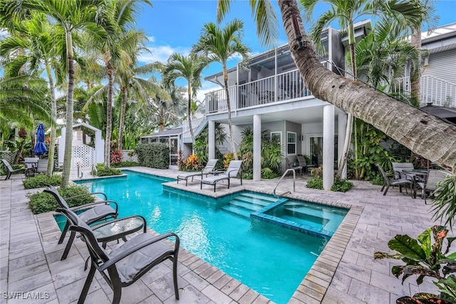 view of swimming pool with an in ground hot tub, a patio, and a sunroom