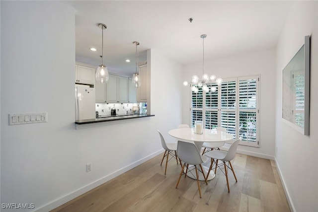 dining area with a chandelier and light hardwood / wood-style flooring