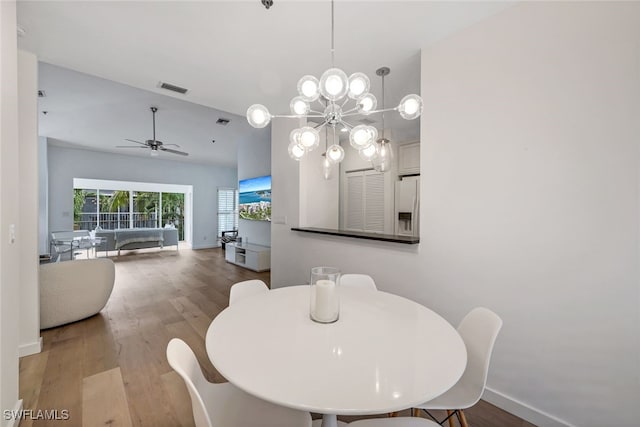 dining area with hardwood / wood-style flooring and ceiling fan with notable chandelier