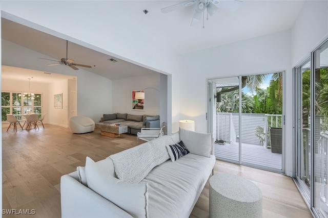 living room with ceiling fan, lofted ceiling, and light wood-type flooring