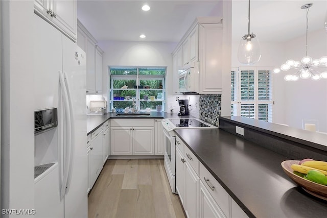 kitchen with hanging light fixtures, white cabinetry, sink, and white appliances