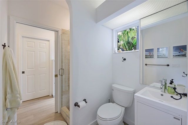 bathroom with a shower with door, vanity, hardwood / wood-style floors, and toilet