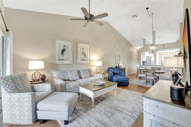 living room featuring light hardwood / wood-style floors, lofted ceiling, and ceiling fan with notable chandelier