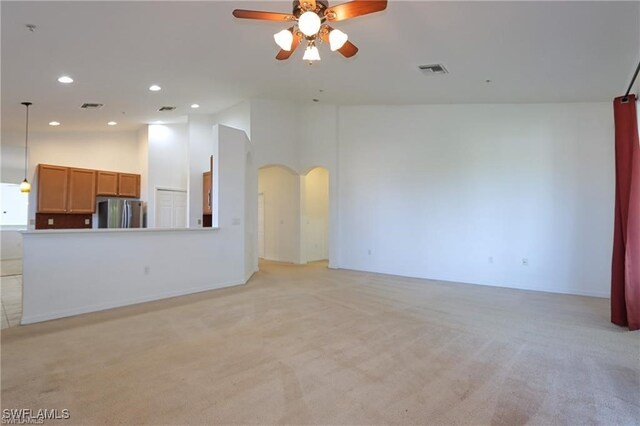 unfurnished living room featuring light carpet, ceiling fan, and high vaulted ceiling