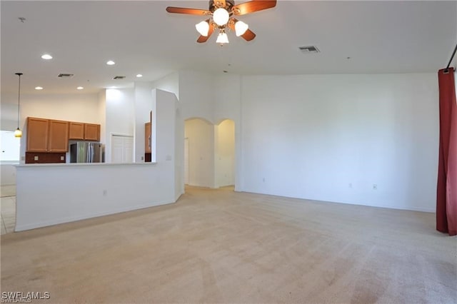 unfurnished living room featuring high vaulted ceiling, light colored carpet, and ceiling fan