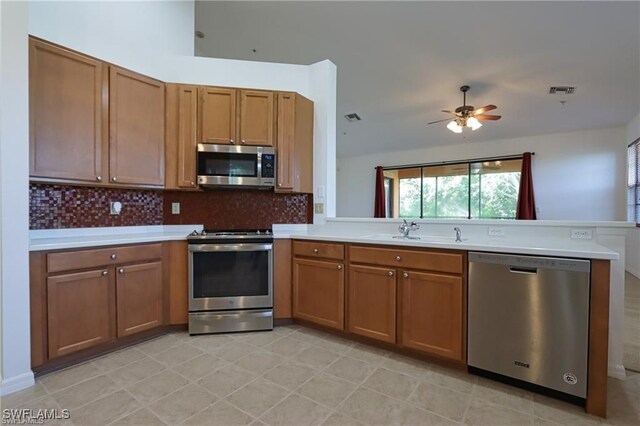 kitchen featuring stainless steel appliances, kitchen peninsula, tasteful backsplash, and sink