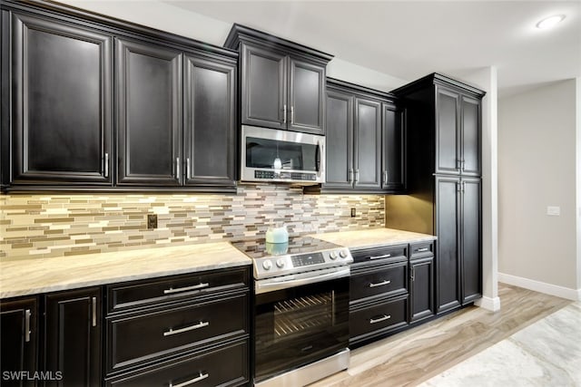 kitchen with light stone counters, backsplash, light hardwood / wood-style flooring, and stainless steel appliances