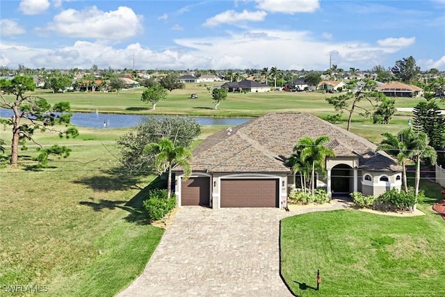 view of front of house with a garage, a front lawn, and a water view