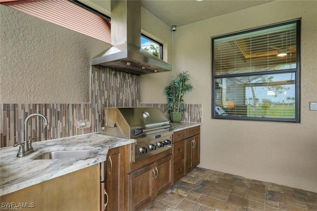 kitchen featuring decorative backsplash, sink, light stone counters, and island range hood