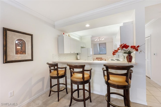 kitchen with white cabinetry, white fridge, backsplash, ornamental molding, and kitchen peninsula