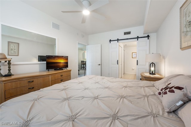 bedroom with ceiling fan, ensuite bath, and a barn door