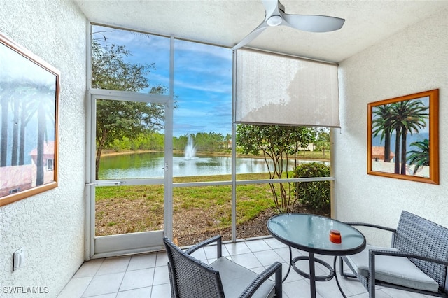 sunroom with ceiling fan and a water view