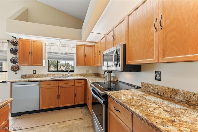 kitchen with appliances with stainless steel finishes, lofted ceiling, light stone counters, and sink