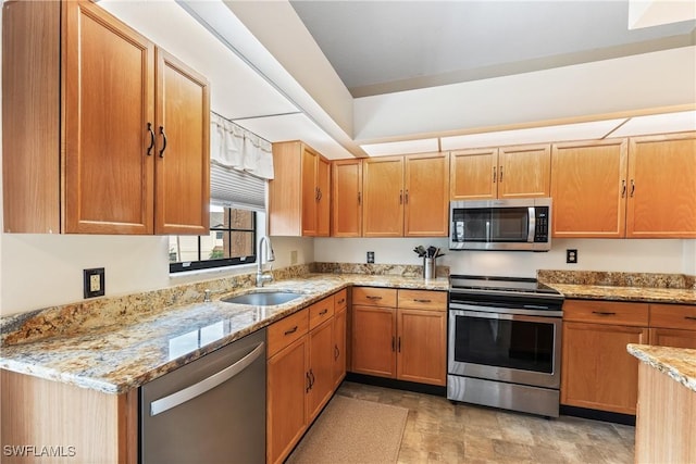 kitchen with appliances with stainless steel finishes, light stone counters, and sink