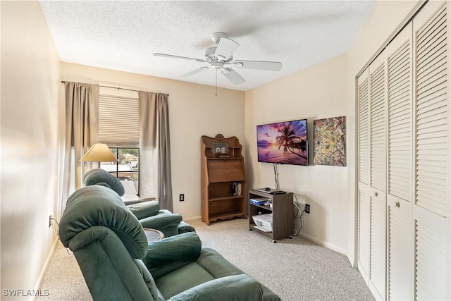 living room featuring ceiling fan, light colored carpet, and a textured ceiling