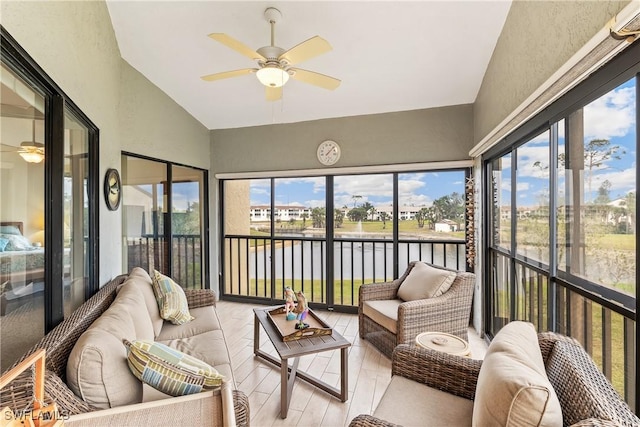 sunroom / solarium featuring ceiling fan, a water view, and vaulted ceiling