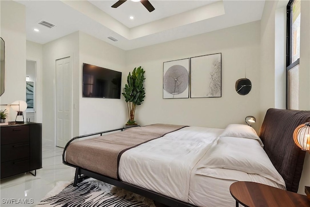 bedroom with ceiling fan, a closet, and a tray ceiling