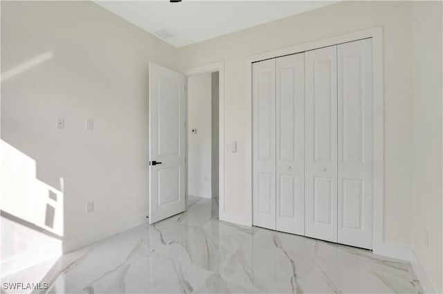 unfurnished bedroom with marble finish floor, a closet, visible vents, and baseboards