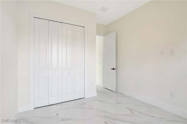 unfurnished bedroom featuring a closet, marble finish floor, visible vents, and baseboards