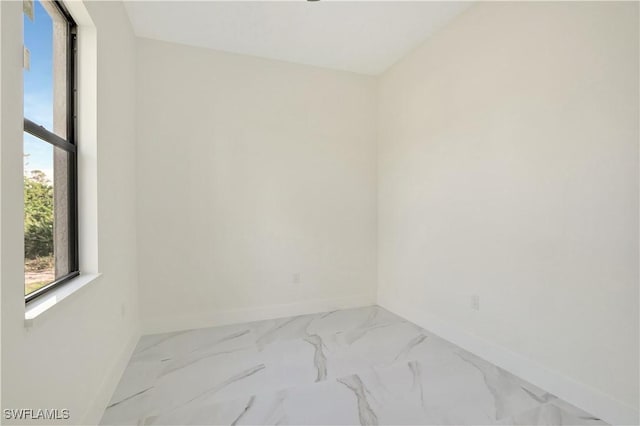 empty room featuring marble finish floor and baseboards