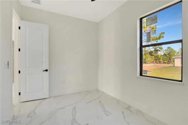 spare room with marble finish floor, visible vents, and baseboards