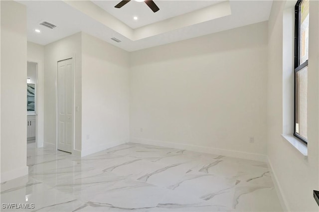 empty room with recessed lighting, visible vents, baseboards, marble finish floor, and a raised ceiling