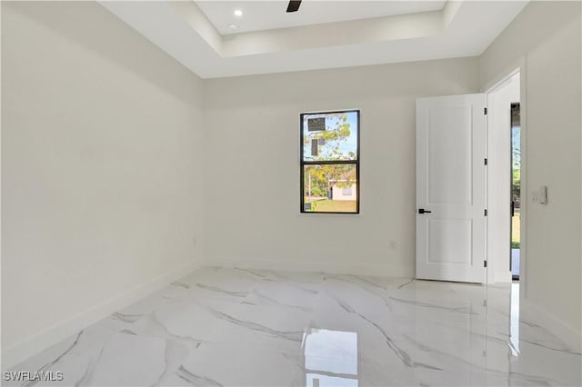 unfurnished room featuring marble finish floor, a tray ceiling, recessed lighting, and baseboards