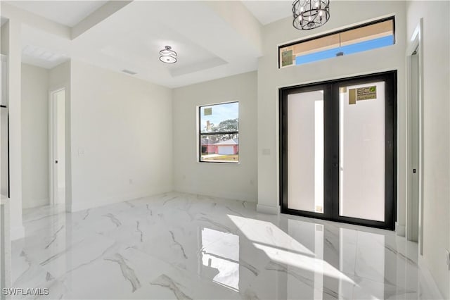 entryway with marble finish floor, a raised ceiling, a notable chandelier, and french doors