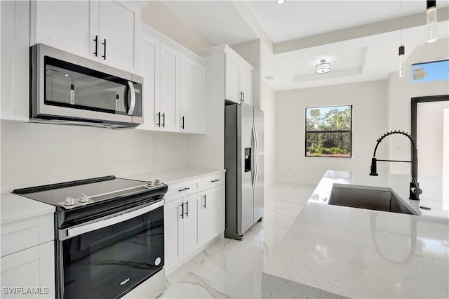 kitchen with a sink, white cabinetry, marble finish floor, appliances with stainless steel finishes, and light stone countertops