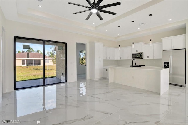 kitchen with marble finish floor, stainless steel appliances, a sink, and a raised ceiling