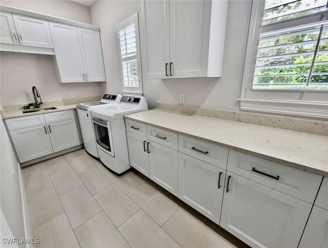 washroom featuring washing machine and dryer, cabinets, light tile patterned flooring, and sink