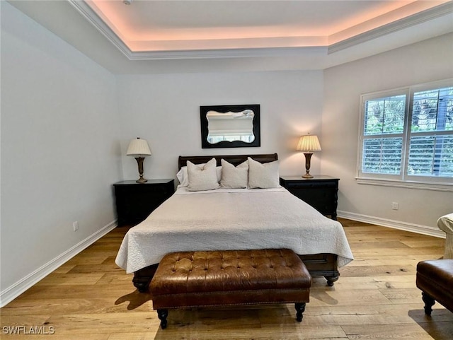 bedroom with light hardwood / wood-style flooring and a raised ceiling