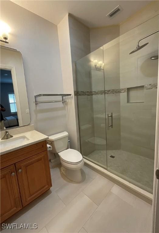 bathroom with vanity, a shower with shower door, tile patterned floors, and toilet